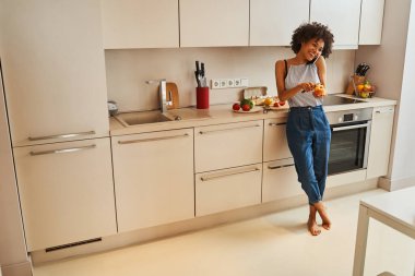 Telefon görüşmesi sırasında elma soyan neşeli bir kadın.