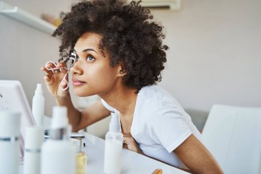 Kirpik bigudi kullanan sakin bir kadın.