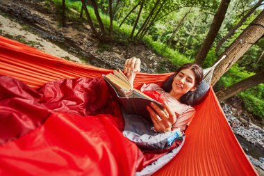 Açık havada kitapla rahatlayan mutlu genç bir kadın.