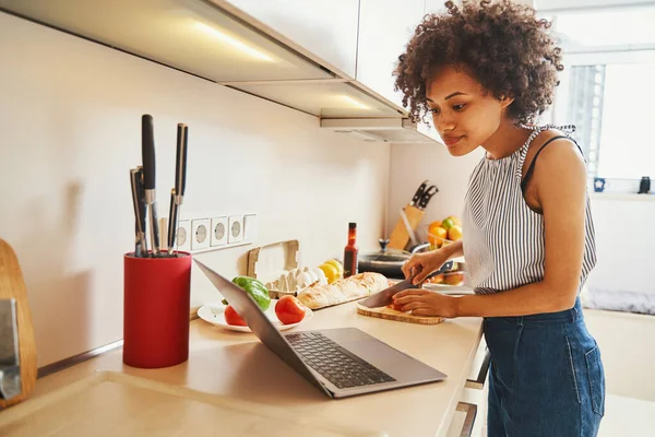 Belle dame faisant une salade de légumes suivant une recette en ligne — Photo