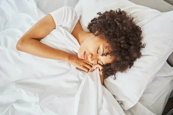 Красивая спокойная женщина с вьющимися волосами дремлет на подушке — стоковое фото