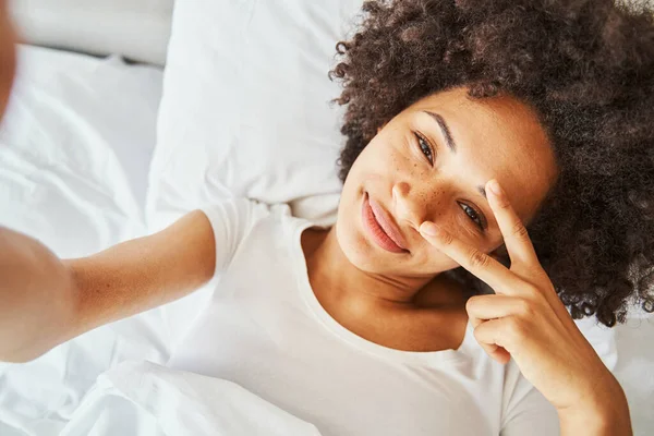 Serena senhora posando para uma selfie na cama — Fotografia de Stock