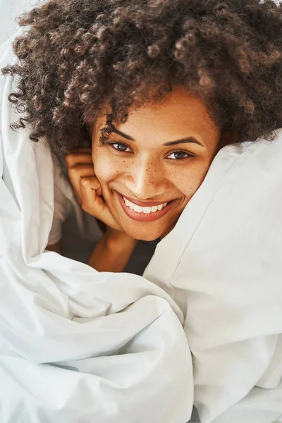 ベッドの上に寝そべっている元気の良い美しい黒髪の女性 — ストック写真