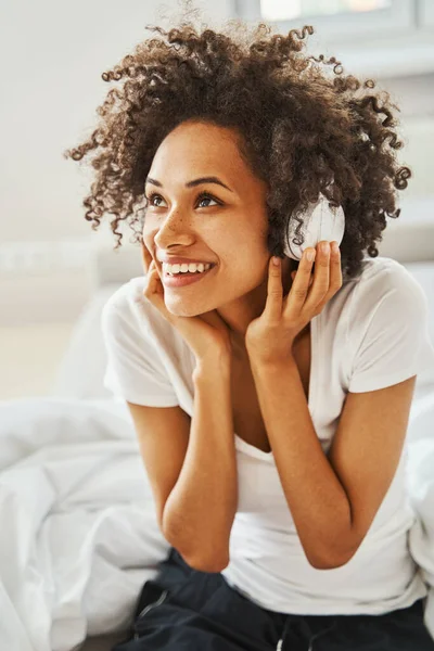 Mulher de espírito elevado em fones de ouvido sem fio ouvindo sua música favorita — Fotografia de Stock