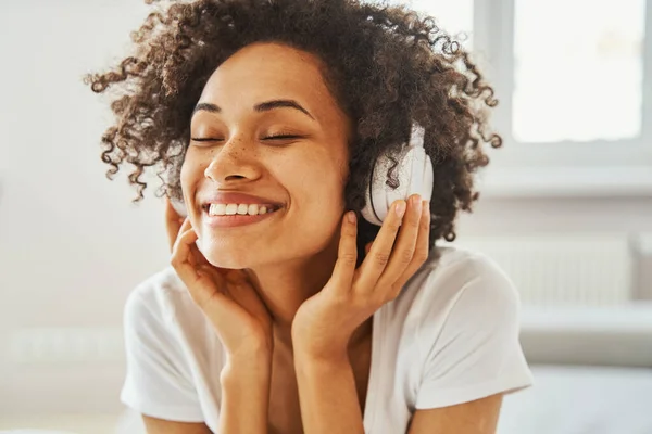 Mulher afro-americana alegre usando fones de ouvido sem fio — Fotografia de Stock