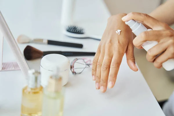 Adult dark-skinned woman applying a beauty product — Stock Photo, Image