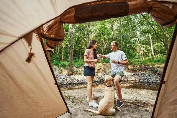 Allegro giovane coppia con tenda e cane nella foresta — Foto Stock