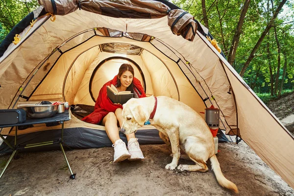 Donna allegra con libro e cane in campeggio — Foto Stock