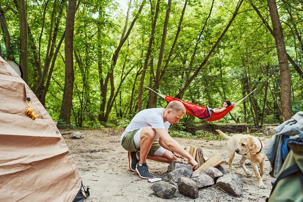 Buoni turisti che si rilassano con cane sul campo — Foto Stock