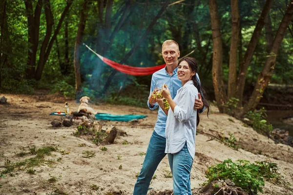 Sorridente giovani amanti durante il picnic nella foresta — Foto Stock