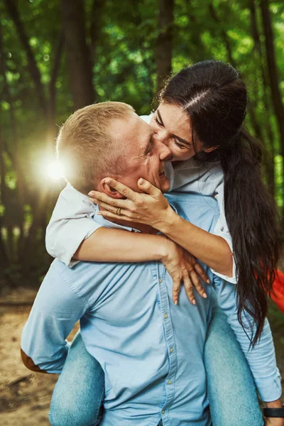 Mulher amorosa beijando namorado na floresta ensolarada — Fotografia de Stock