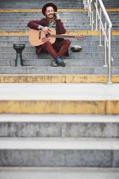 Bonito jovem músico tendo agradável conversa telefônica — Fotografia de Stock