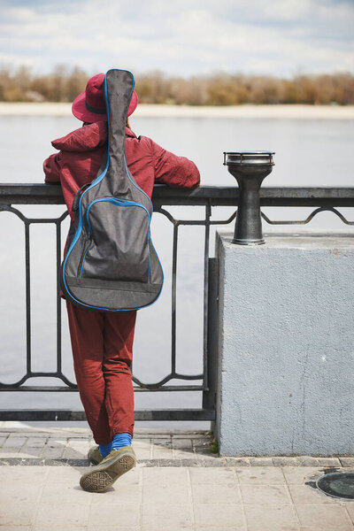 Dreamy street musician looking at the river