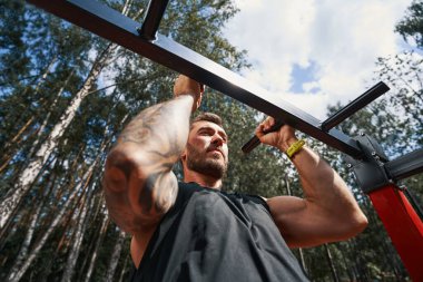 Motive olmuş genç vücut geliştirici dışarıda vücut geliştirme eğitimi alıyor.