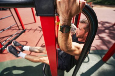 Güçlü yakışıklı vücut geliştirici dışarıda vücut egzersizi yapıyor.