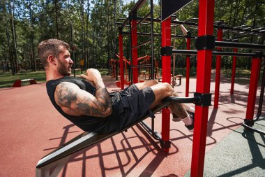 Genç güçlü bir adam spor alanında karın kaslarını çalıştırıyor.