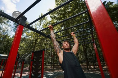 Genç ve güçlü bir adam parkta spor yapıyor.