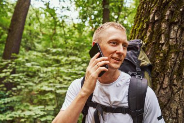 Neşeli genç adam ormanda çağrı yapıyor.