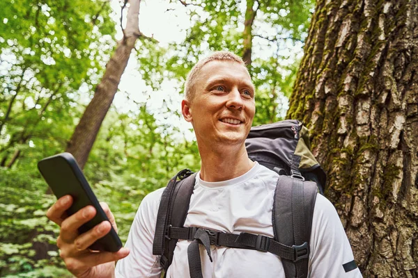 Gelukkige jongeman met smartphone in de natuur — Stockfoto