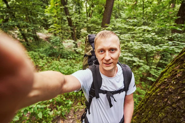 Vrolijke kerel neemt selfie in groen bos — Stockfoto