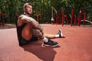 Güçlü genç adam dışarıda antrenman yaparken dinleniyor.