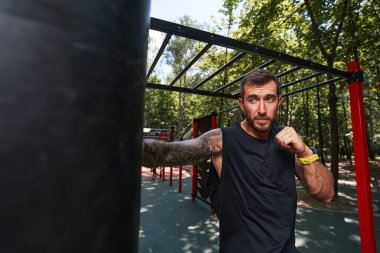 Neşeli genç adam dışarıda boks yapıyor.