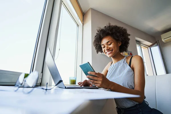 Nöjd kvinnlig frilansare läser ett sms på jobbet — Stockfoto