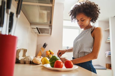 Ciddi, güzel, siyah saçlı kadın akşam yemeğini hazırlamaya odaklanmış.