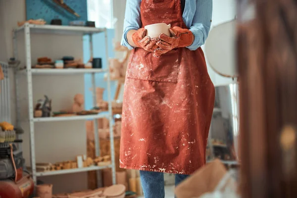 围裙中的女性陶工手持手工制作的黏土碗 — 图库照片