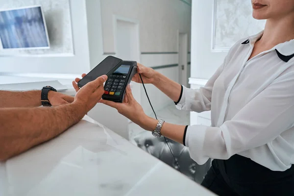 Beauty salon customer making a contactless payment at the reception counter — Stock Photo, Image