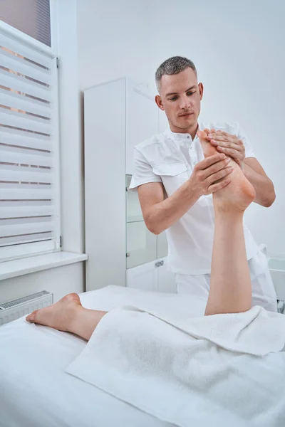 Fisioterapista concentrato esperto che utilizza un massaggio di digitopressione — Foto Stock