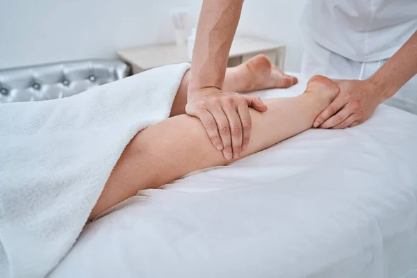 Masoterapeuta dando a su paciente un masaje en la pierna — Foto de Stock