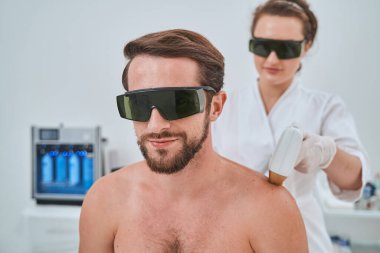 Kozmetik ameliyat sırasında koruyucu gözlüklü bir erkek hasta.