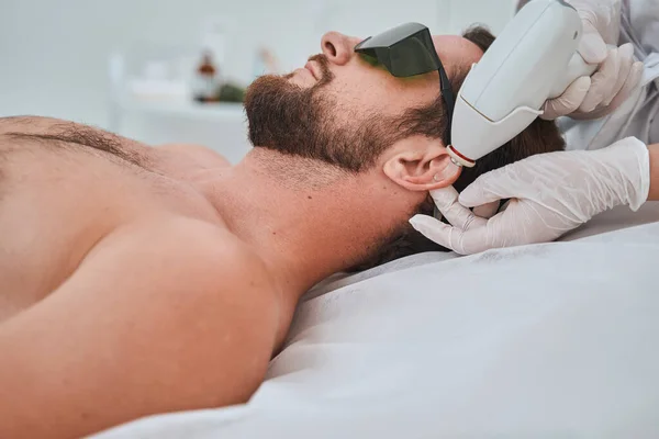 Paciente jovem em óculos de proteção submetido a um procedimento cosmético — Fotografia de Stock