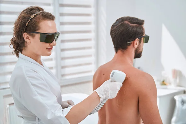 Médica em óculos de segurança realizando um procedimento estético — Fotografia de Stock