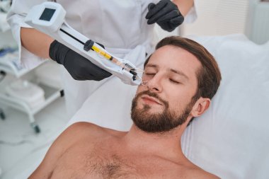 Bir güzellik kliniğinde cilt yenileme tedavisi gören bir adam.