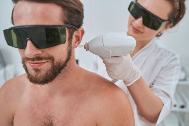 Koruyucu gözlüklü bir erkek hasta estetik ameliyat geçiriyor.