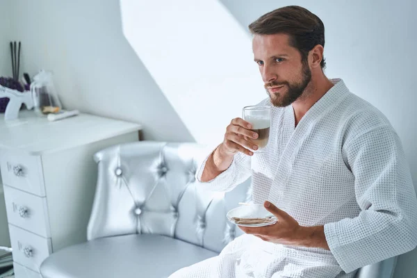 Muž pije vrstvené latté macchiato před kosmetickou procedurou — Stock fotografie