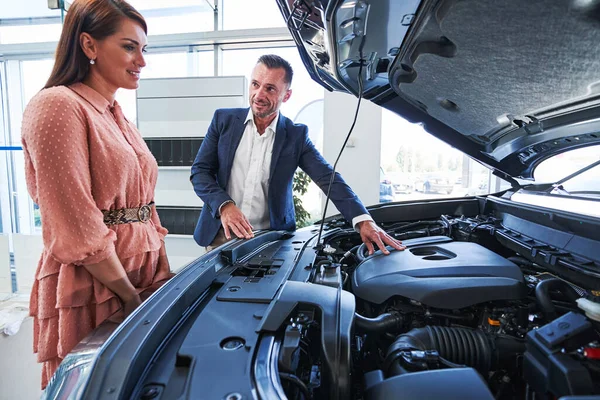 Cliente mujer curiosa estudiando las partes de su futuro coche — Foto de Stock