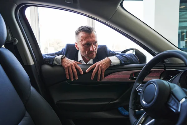 Serious person looking inside the car and frowning — Stock Photo, Image