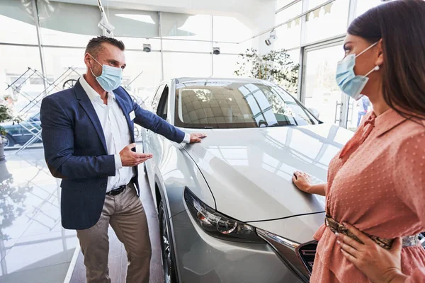 Professional salesman consulting his client in car showroom — Stock Photo, Image