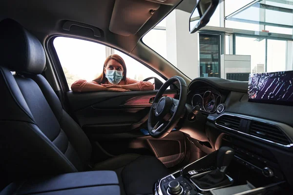Ung kvinna tittar på den nya bilen från insidan — Stockfoto