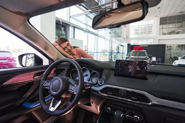 Drömmande kvinna beundrar sin nya bil i showroom — Stockfoto