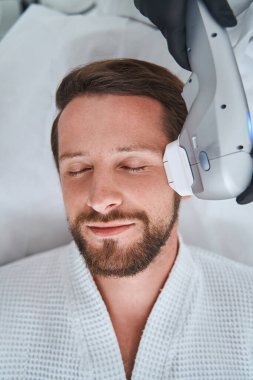 Cilt sıkma işlemi sırasında rahatlayan erkek spa istemcisi