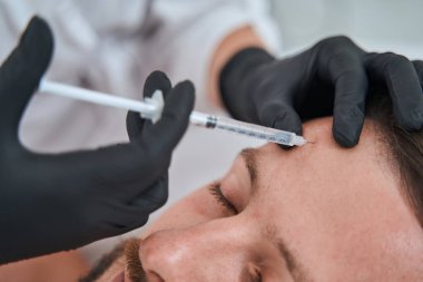 Adamın alnına deri altı enjeksiyonu yapılıyor.