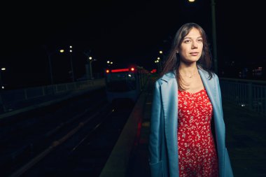 Geceleyin demiryolu platformunda duran bir kadın