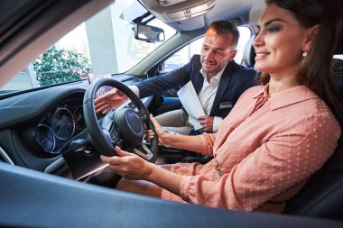 Kadın sürücü yeni modern arabasından memnun görünüyor.