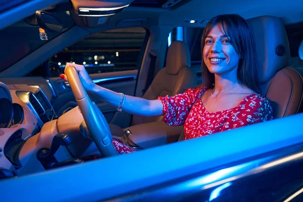 Cheerful young woman driving car at night — Stock Photo, Image