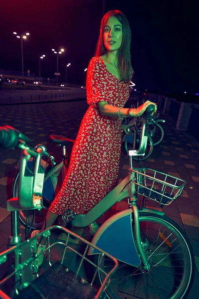 Kobieta z rowerem stojąca nocą na ulicy — Zdjęcie stockowe