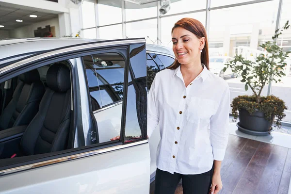 Cheerful saleswoman inviting you to the car salon — Stock Photo, Image